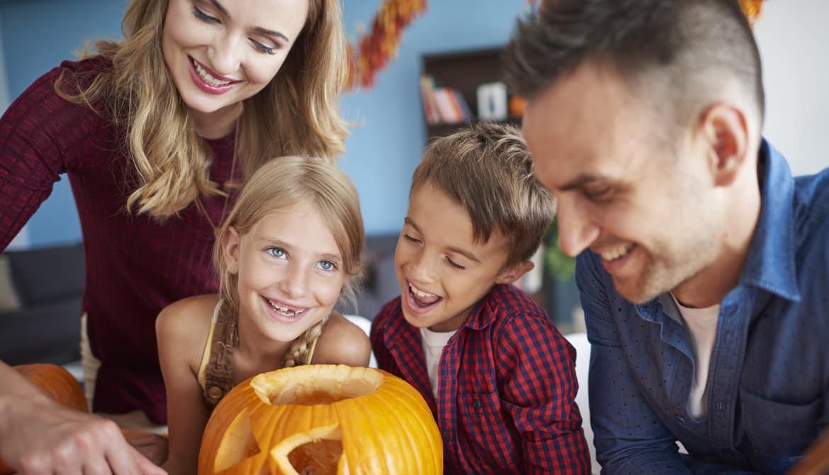 Famille qui creuse une citrouille pour préparer Halloween à Foix